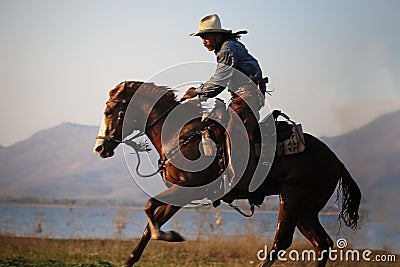 Cowboy on his horse walking through dust in the desert Stock Photo