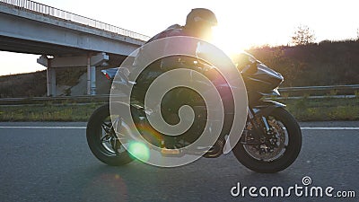 Man riding on modern sport motorbike at highway with sun flare at background. Motorcyclist racing his motorcycle on. Country road. Guy driving bike during trip stock footage Man riding on modern sport motorbike at highway with sun flare at background. Motorcyclist racing his motorcycle on. Country road. Guy driving bike during trip stock footage