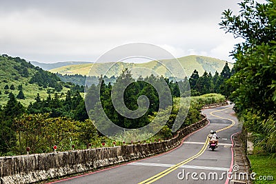 Man riding a motorcycle down a curvy road with a passenger behind Editorial Stock Photo