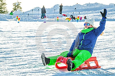 A man riding on a red sled descends down the mountain Stock Photo