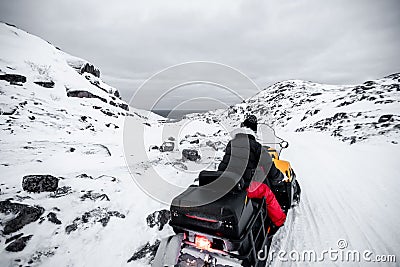 A man is riding snowmobile in mountains. Beautiful morning light. A winter ride on a snowmobiles, winter landscape Stock Photo