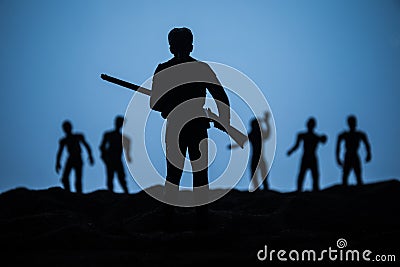 Man with riffle against zombie attack. Zombie apocalypse. Scary view of blurred zombies at cemetery and spooky cloudy sky with fog Stock Photo