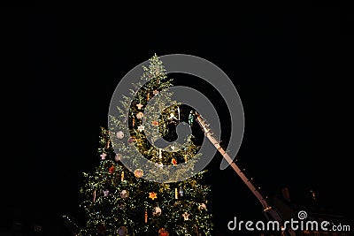 Man on the rising platform gigantic crane decorating Christmas tree Editorial Stock Photo