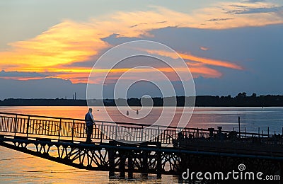 Man on river quay at sunset, Rybinsk, Russia Stock Photo