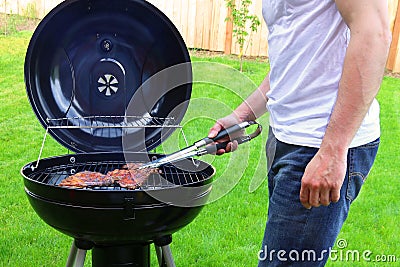 Man roasting beef on BBQ grill Stock Photo