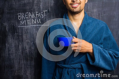 Man in robe next to breakfast menu on blackboard Stock Photo