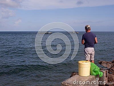 Man rod fishing at the end of the concrete fishing pier Editorial Stock Photo