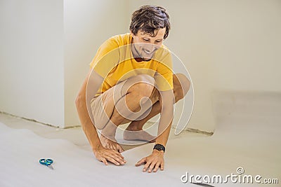 man and a roll of insulating cloth to install a laminate wooden floor Stock Photo