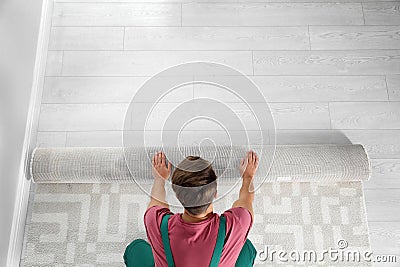 Man rolling out new carpet flooring indoors, top view. Stock Photo