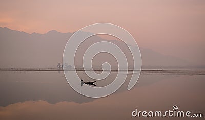 Man rowing his boat on a Peaceful Sunrise Stock Photo