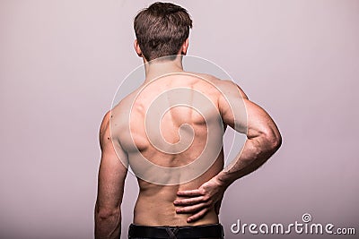 Man rubbing his painful back on grey . Pain relief, chiropractic concept Stock Photo