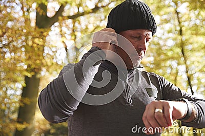 Man On Run Checking Activity Tracker And Putting In Earphones Stock Photo