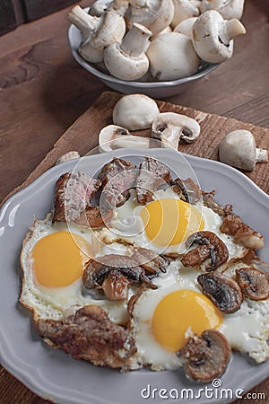 A man `s breakfast, a egg with mushrooms and meat for breakfast - this is a wonderful beginning of the day. Stock Photo