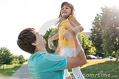 A man`s father, holding a child in his arms and throwing up a girl, years in the city, happy laughing rejoice and have Stock Photo