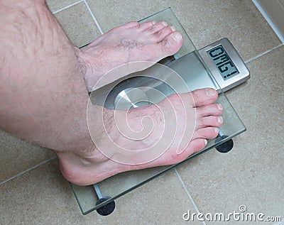 Man's feet on weight scale - OMG Stock Photo