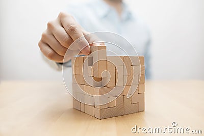 Man`s hand adding the last missing wooden block into place. Stock Photo