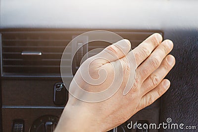 Man`s hand on car heater or conditioner, regulates temperature in automobile while drives. Car`s accessories or panel. Conditionin Stock Photo