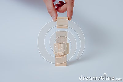 Man`s hand completing set of 4 stacked wooden cubes, concept Stock Photo