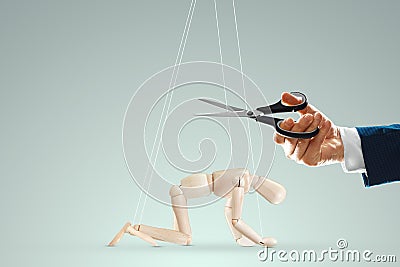 A man`s hand cuts the threads between the puppeteer and the puppet with scissors. The concept of liberation from slavery, freedom Stock Photo