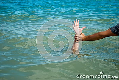 A man`s hand drowns in water calling for help, man helps rescue, against the background of the sea Stock Photo