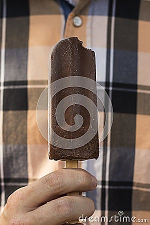 Man's hand hoding a bitten chocolate ice-lolly Stock Photo