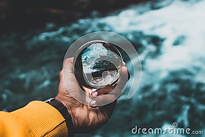 Man's hand holding a crystal ball reflecting nature Stock Photo
