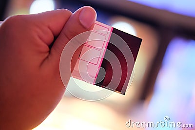 Man`s hand holding a paper ticket on blurred cinema complex back Stock Photo