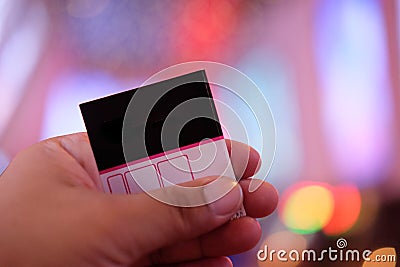 Man`s hand holding a paper ticket on blurred cinema complex back Stock Photo