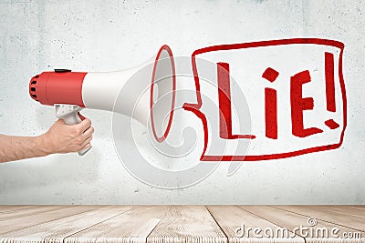 Man`s hand holding red and white megaphone against grungy white wall with big speech bubble that says `Lie` Stock Photo