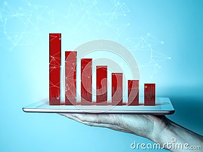 Man`s hand holding a tablet. The screen shows a 3d graph in the form of red columns illustrating the fall or decline Stock Photo