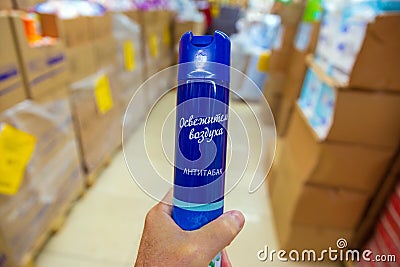 a man`s hand holds an air freshener while choosing in a store. Russian text: air freshener, anti-tobacco Editorial Stock Photo