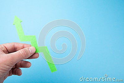 The man`s hand holds the arrow up as a sign of success. Blue background Stock Photo