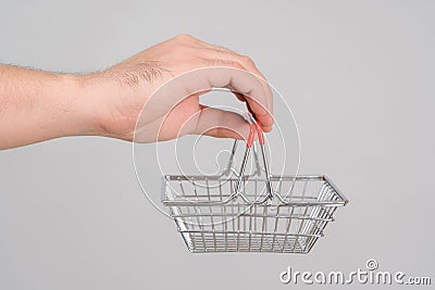 A man`s hand holds a miniature shopping basket Stock Photo