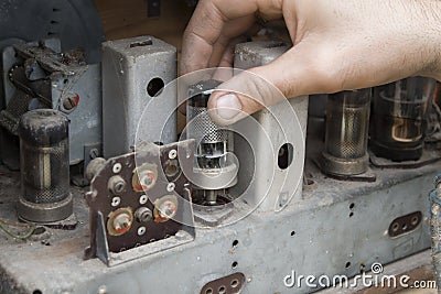 Man`s hand mounts the lamp to the old vintage tube radio. Stock Photo