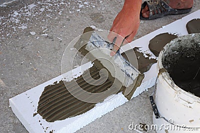 Man's Hand Plastering a Wall Styrofoam or Foam Board Insulation with Trowel. Styrofoam Insulation for Basement Walls. Stock Photo