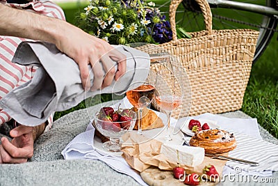 Man`s hand pouring rose wine into glasses, summer picnic Stock Photo