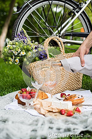 Man`s hand pouring rose wine into glasses, summer picnic Stock Photo