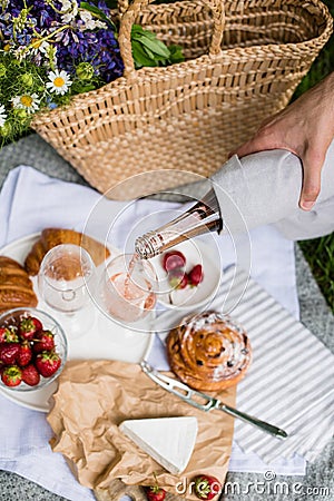 Man`s hand pouring rose wine into glasses, summer picnic Stock Photo