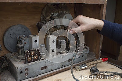 Man`s hand pulls out the lamp from the old vintage tube radio. Stock Photo