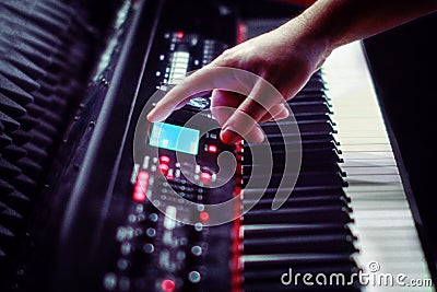 A man`s hand shows on the electronic scoreboard piano Synthesizer stands in the recording Studio. Large white and black keys Stock Photo