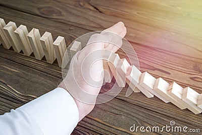The man`s hand stops the domino effect. Stock Photo