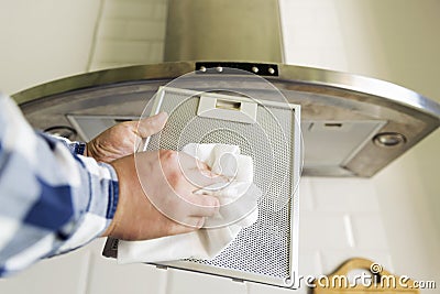 Man`s hands cleaning aluminum mesh filter for cooker hood. Housework and chores. Kitchen cooker hood on the background Stock Photo