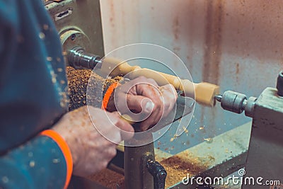 Man`s hands hold chisel near lathe, man working at small wood lathe, an artisan carves a piece of wood using a manual lathe Stock Photo