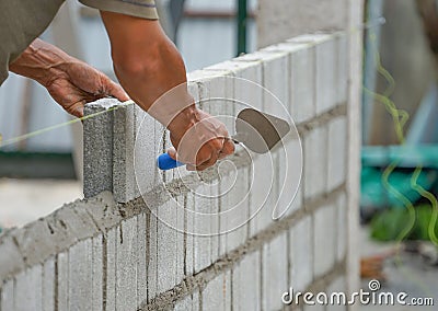 Man`s hands of industrial bricklayer with aluminium brick trowel installing brick blocks on construction site Stock Photo