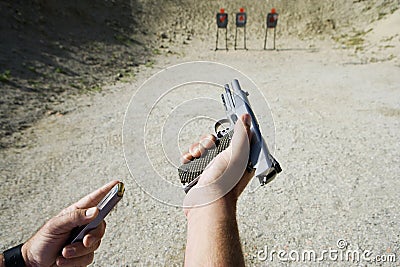 Man's Hands Loading Gun At Firing Range Stock Photo