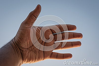 A man's left palm against sky Stock Photo