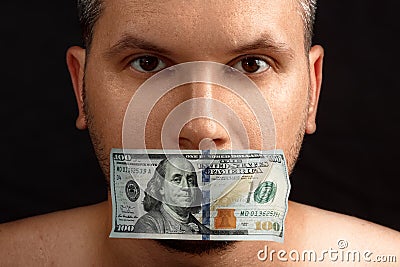 The man`s mouth is sealed with dollars, money. The concept of buying silence, corruption, lobbyists for money Stock Photo