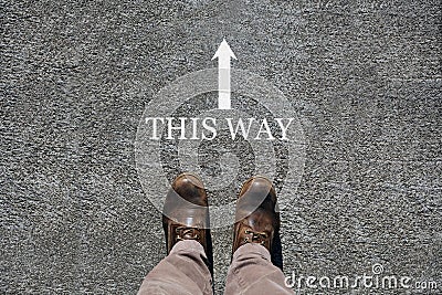 Man`s shoes view from above, words this way and an arrow indicating the directions with copy space for text Stock Photo