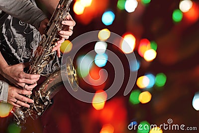 Man`s and woman`s hands with saxophone on bokeh lights Stock Photo