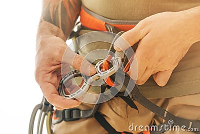 Man in safety harness attaches a figure of eight device to carabiner. Stock Photo